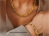En person iført en chunky guldkæde og et matchende armbånd, klædt i et beigefarvet outfit. Teksten siger: Chunky halskæde og armbånd.