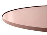 Nærbillede af en rund, pink metalbordplade med hævet kant, vist i en vinkel mod en hvid baggrund.