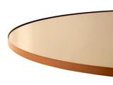 Nærbillede af et rundt bord med en glat, reflekterende beige overflade og en tynd, brun kant mod en hvid baggrund.