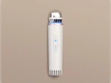 En slank, cylindrisk hvid håndholdt enhed med en metallisk top, blåt lys og kontrolknapper, placeret lodret på en beige baggrund.
