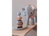 En grå elefant i plys står ved siden af en træabe, der kan stables, med striber og en blå bold på toppen, begge placeret på en træoverflade.