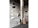 Hængende keramikskåle, hvide og sorte, i et minimalistisk betonrum med tæpper, bøger, en vase, kunstværker og en skammel med et stearinlys.