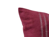 Nærbillede af en rødbrun pude med struktureret stof og to tynde, lodrette sølvstriber på højre side.