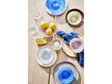 Farverige glasskåle, citroner, smør, et blåternet klæde, to glas og en skål med salt står på et lyst træbord.