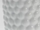 Nærbillede af en hvid, struktureret overflade med et gentagende mønster af hævede, afrundede buler, der ligner en bikage eller en golfbold.