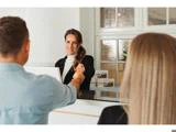 En receptionist giver en nøgle til en mand på den anden side af skranken, mens en kvinde står ved siden af ham i et lyst og indbydende receptionsområde.