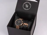 Et armbåndsur i sort og guld med netrem og en ekstra læderrem i en sort Schmidt Watches-æske.