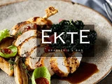 Stegt kylling i skiver med grønt, grøntsager og sauce på en rustik tallerken. Teksten "EKTE Brasserie & Bar" er lagt oven på billedet.