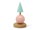 En minimalistisk skulptur med en lyseblå kegle på toppen af en messingstang, en pink kugle og en rund træbase på en hvid baggrund.
