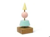 En geometrisk skulptur med en firkantet træbase, toppet af en lyseblå trapez, en pink kugle og en gul kegle, som alle er stablet lodret på en metalstang.