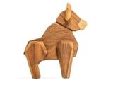 En geometrisk træskulptur af en tyr eller bøffel, lavet af lyse og mørke træstykker, der står oprejst på en hvid baggrund.