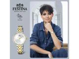 En kvinde i denimtøj bærer et Festina-ur i guld og sølv, mens hun sidder og smiler. I reklamen står der Festina Watches since 1902, og der er et nærbillede af uret og Miss France 2024 Eve Gilles.