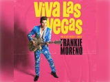 En mand i et blåt blomstret jakkesæt, der holder en guitar, står foran en lyserød baggrund med stor gul tekst: »Viva Las Vegas«, som reklamerer for »The Elvis Presley Show« med Frankie Moreno….