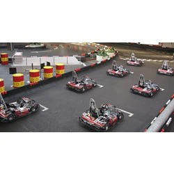 Flere gokarts er linet op på startgridden i en indendørs gokartbane, klar til et løb.