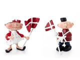 To finurlige keramikfigurer, en pige og en dreng, der hver især holder et dansk flag. Pigen er iført rød kjole og sløjfe, og drengen er iført uniform med sort hat.