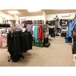 Interiør i tøjbutik med stativer med jakker, farverige hættetrøjer, støvler og forskelligt tilbehør udstillet på vægge og hylder.