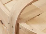 Nærbillede af en trækurv med buet hank og flettede lameller, der viser metalklammer, der fastgør håndtaget til kurven.