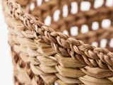 Nærbillede af en vævet kurv lavet af naturlige, flettede fibre, der viser detaljeret tekstur og håndværk med en sløret baggrund.