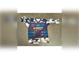 Blå og hvid sportstrøje i camouflagemønster med sponsorlogoer, et stjernemotiv og teksten Energy på forsiden, lagt fladt på en grå overflade.