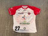 En rød og hvid sportstrøje med nummer 27 og forskellige sponsorlogoer, herunder Rema 1000 og 2R Sportshop.