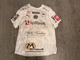 Hvid fodboldtrøje med korte ærmer og forskellige sponsorlogoer, herunder Sydbank, Smith Knudsen og Østermark.