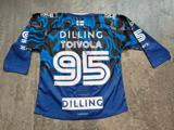 En blå og sort ishockeyskjorte med påskriften »DILLING«, »TOIVOLA« og nummeret 95 på ryggen, der ligger fladt på et betongulv.