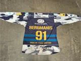 En blå, hvid og grå hockeytrøje i camouflagemønster med teksten Bergmanis 91 og WHEN WE STAND TOGETHER trykt på ryggen, der ligger fladt på et betongulv.