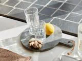 To glas stablet oven på hinanden, en citron og et stykke ingefær på et lille, mørkt, rundt serveringsbræt.