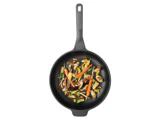 En non-stick-pande med sauterede grøntsager, herunder gulerødder, rosenkål og svampe.