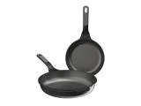 To sorte non-stick-stegepander, hvoraf den ene står vandret i forgrunden, og den anden står lodret bagved.