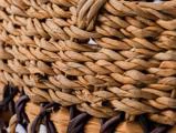 Nærbillede af en flettet kurv, der viser tæt sammenflettede naturfibre i lyse og mørkebrune nuancer.