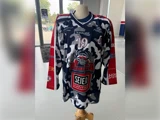 En ishockeytrøje i camouflagemønster i blå, hvid og grå med nummer 19 og et rensdyrlogo for Ringsted, udstillet på en mannequin.