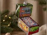 En julekugle af glas formet som en flippermaskine med teksten Merry Christmas på bagpladen.