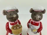 To keramiske musefigurer klædt ud som kokke; den ene holder en kage med hvide prikker, den anden holder en skål og et piskeris. Begge har rødt tøj på med hvide forklæder og kokkehuer.