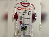 En hvid og rød sportstrøje med forskellige sponsorlogoer, tallet 6 og navnet BO hænger på en sort bøjle mod en lys væg.