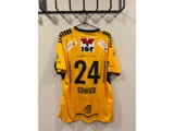 En gul sportstrøje med sorte striber, nummer 24 og navnet EDWIGE, der hænger på en krog. Der ses forskellige sponsorlogoer på bagsiden af trøjen.