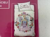 Et sengesæt med Barbie-tema med en eventyrlig Barbie med vinger, omgivet af blomster og sommerfugle, på en lyserød baggrund med ordet Barbie skrevet på dynen og puden.