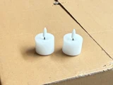 To små hvide LED-stearinlys med spidse toppe er placeret side om side på en almindelig brun papoverflade.