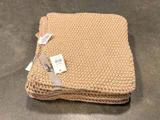 En stak foldede beige strikkede klude med et Mynte-mærke og en stregkodeetiket fastgjort.