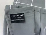 En grå stofvare med hvide striber har en etiket med teksten byrklund basics for living 100% katoen/bomuld/coton.