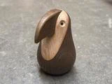En lille, stiliseret fuglefigur af træ med et stort, buet næb.