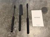 Tre sorte osteknive ved siden af et produktkort fra Normann Copenhagen.
