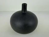 En rund, matsort keramikvase med smal hals og lille åbning, placeret på en lys overflade mod en ensfarvet baggrund.