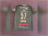En grøn sportstrøje med nummeret 57 og navnet LARSSON, dækket af adskillige sponsorlogoer, lå fladt på en struktureret overflade.