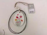 Et ovalt ornament med malede vilde blomster og en jutesnor med træperler, fastgjort til et mærke mærket DIJK.