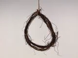 En enkel dråbeformet krans af sammenflettede kviste hænger i en snor mod en almindelig lys baggrund.