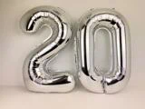 To store sølvfarvede folieballoner formet som tallet 20, der står på en almindelig lys baggrund.