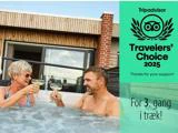 En ældre kvinde og en mand skåler med drinks i et spabad. Ved siden af dem er der en Tripadvisor Travelers' Choice 2025-prisgrafik med dansk tekst, der siger "For 3. gang i træk!".