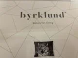 Produktemballage med mærkenavnet byrklund, taglinen basics for living og et billede af en pude med leopardprint.