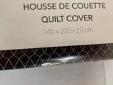 En pakke mærket Housse de Couette Quilt Cover 140 x 220+20 cm med et geometrisk mønster i bunden.